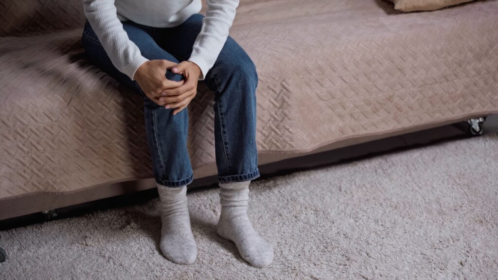 cropped photo of someone sitting and holding their knee in pain