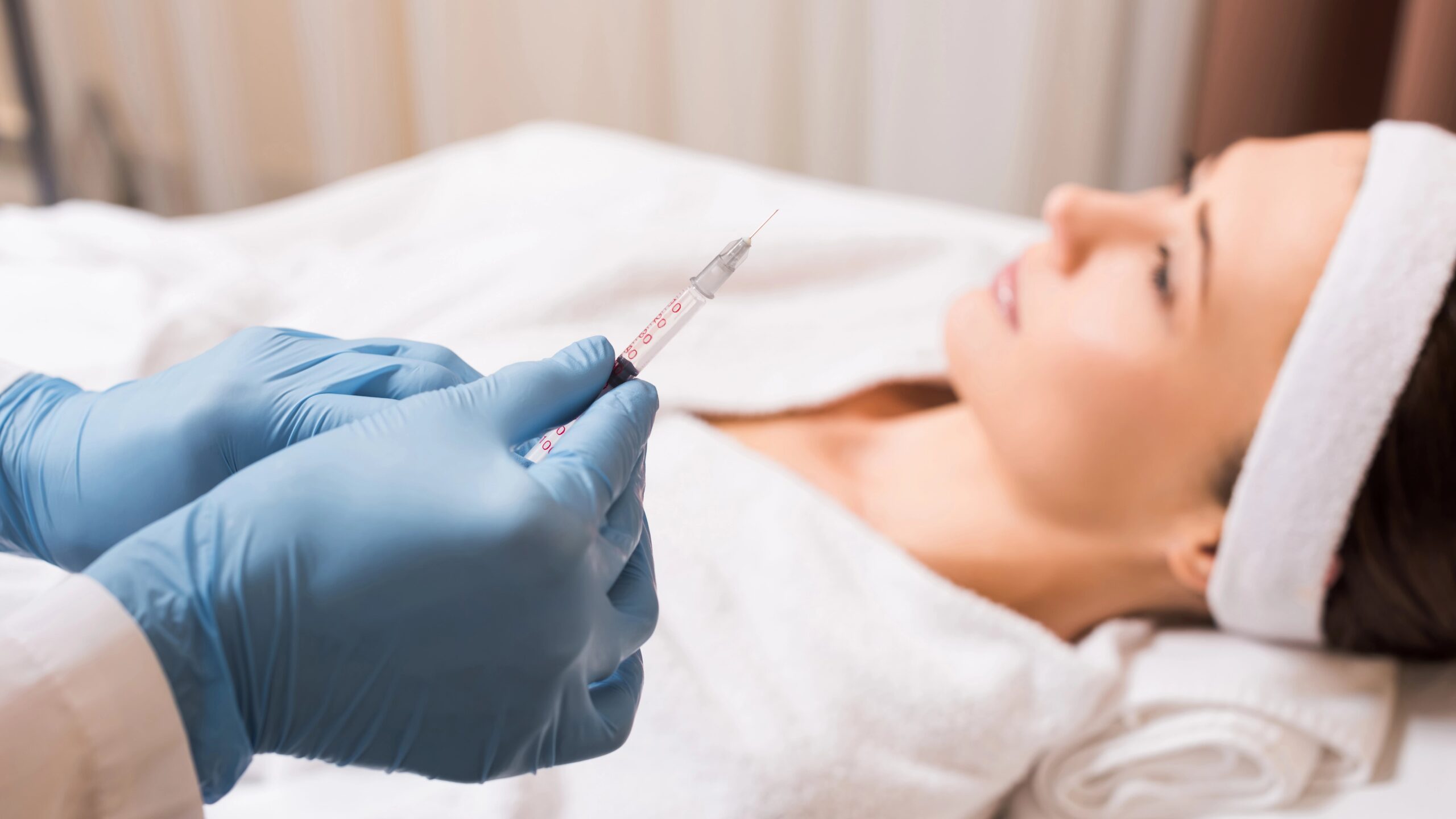 Medical professional holding syringe, female patient in background